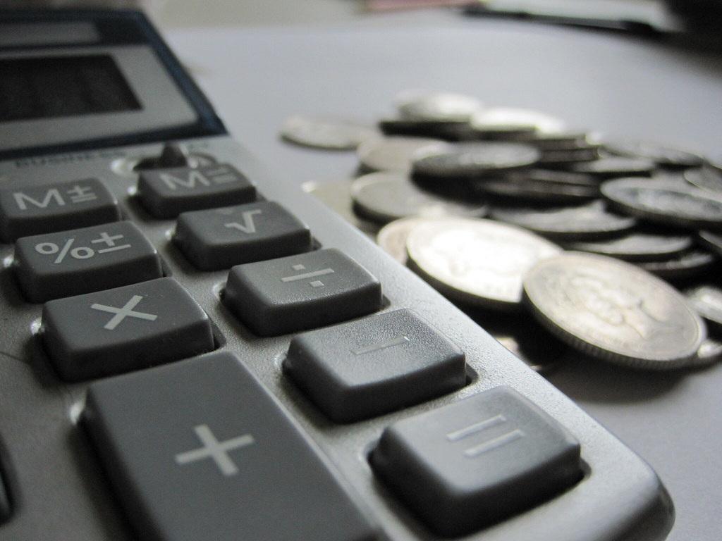 A pocket calculator next to a pile of loose change